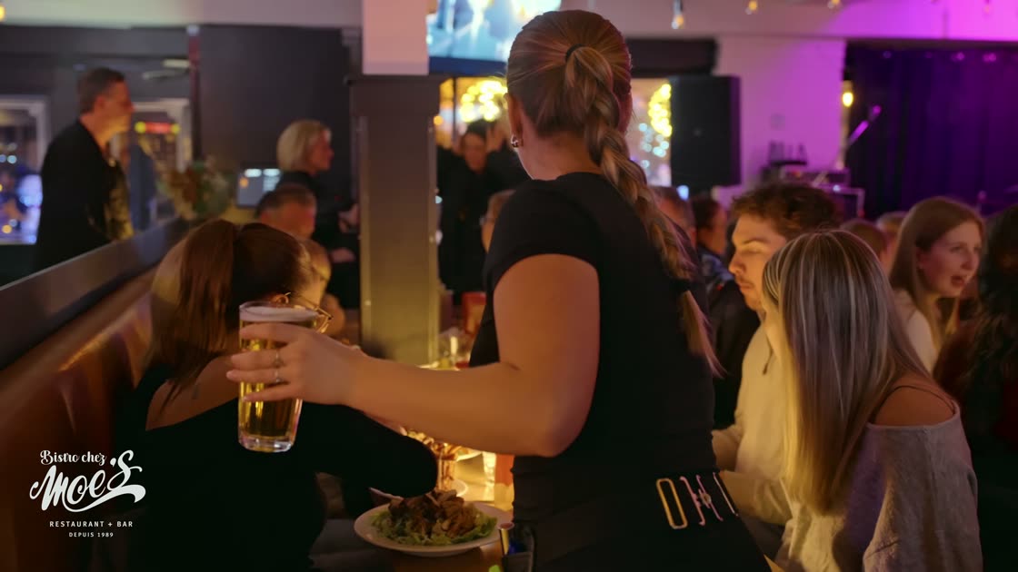A server carries a beer through a full dining room